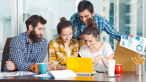 Un grup de quatre persones davant d'un ordinador portàtil