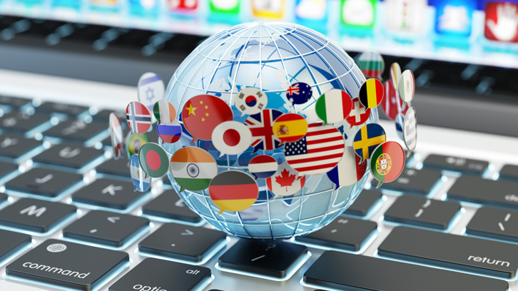 Primer pla de les mans d'una estudiant comparant els seus apunts amb l'ordinador