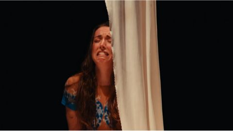 una noia vestida de frozen plorant recolzada a una cortina