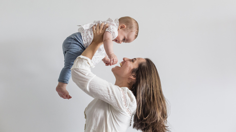 Una mare aixecant a l'aireu un nadó o nena de mesos.