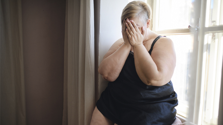 mujer con sobrepeso preocupada con las manos tapándole la cara